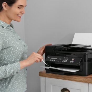 Woman,Using,Modern,Printer,On,Chest,Of,Drawers,At,Home